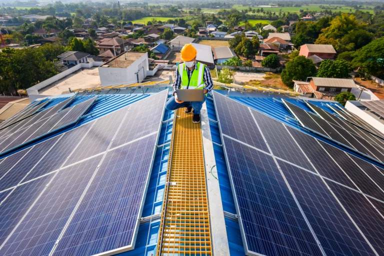 A solar installer crouches down on top of a roof to make sure the panels he put in are working properly.