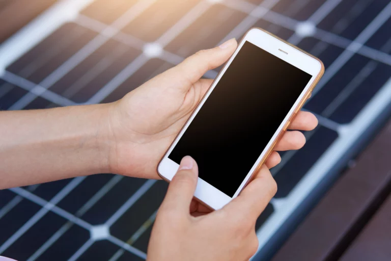 A picture of a woman holding her phone as she prepares to access her solar monitoring app.